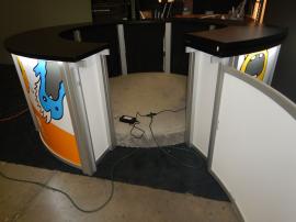 RENTAL: Modified RE-1226 Circular Counter with Black Laminated Top, Curved Locking Door, Black Laminated Shelving, Circular Carpeted Platform, and Direct Print Sintra Graphic Infill Panels.