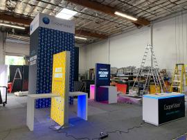 RENTAL: Custom Island Rental Design with (2) 4 ft Wide x 8 ft. High Double-Sided Lightbox Kiosks with 36" x 24" White Laminated Waterfall Workstations with RGB Accent Lighting Underneath, Gravitee System Storage Closet @ 80" x 80" x 190" High with Locking