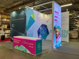 RENTAL: Island Design with Gravitee Conference Room, Storage Closet, Ceiling Canopy, (2) Large Monitor Mounts, (12) LED Arm Lights, (2) RE-1576 White Laminated Reception Counters, SEG Fabric Graphics, and Direct Print PVC Graphics
